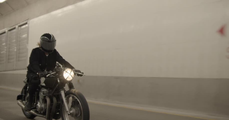 A person rides a motorcycle in the long tunnel