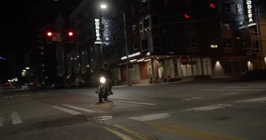 The motorcycle slowly moves down the night street