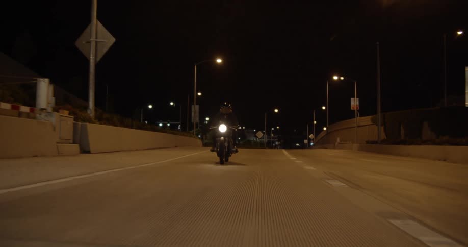 A motorcyclist drives on a city road at night