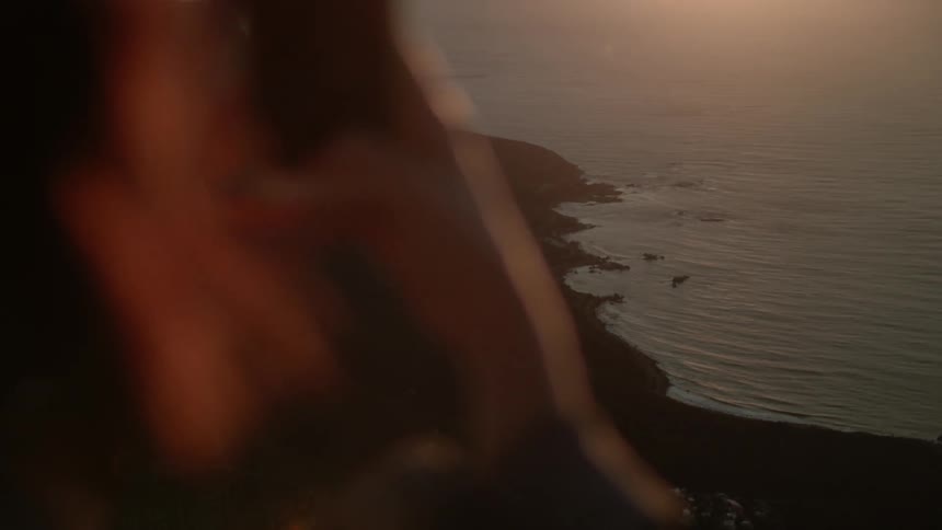 A person takes a cellphone pic of a shoreline at sunset