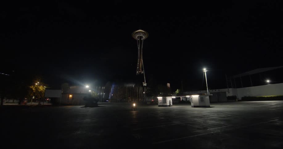 A motorcyclist is stopped in a parking lot at night