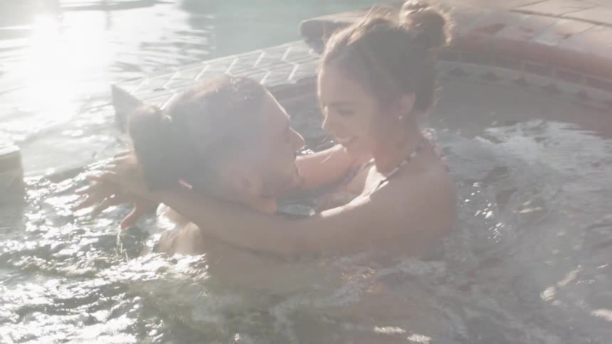 A man and woman hug in the hot tub