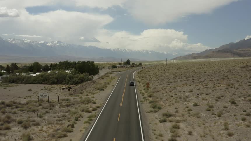 The car drives on the long desert road
