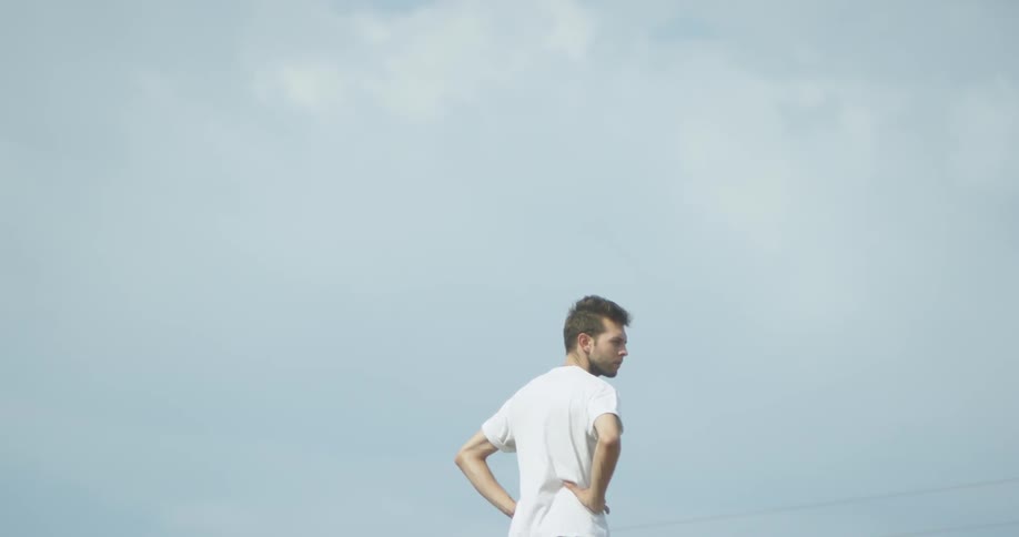 A man is standing with his hands on his hips outside in daylight