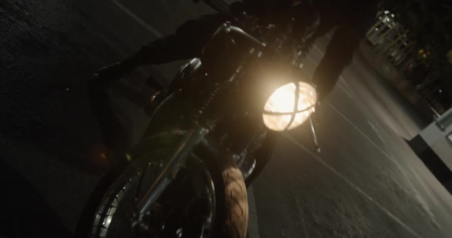The person pulls up on their motorcycle at night