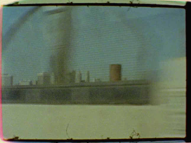 A vehicle crosses a bridge with a city in the distance