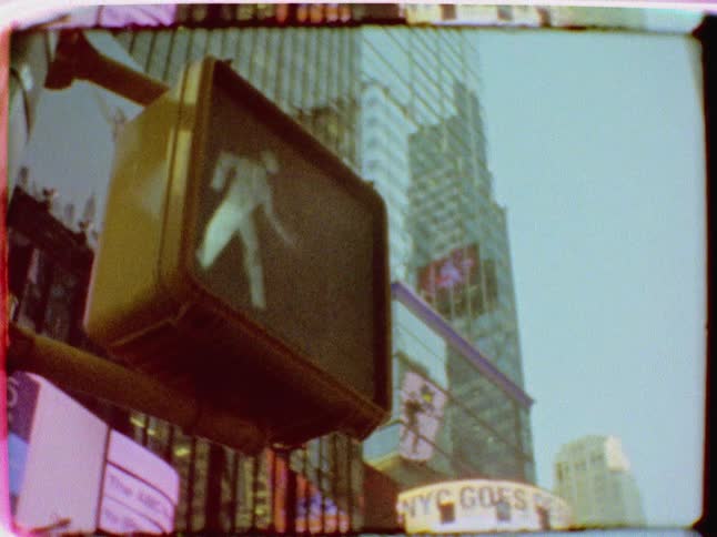 A crosswalk sign showing the walk symbol is highlighted against skyscrapers