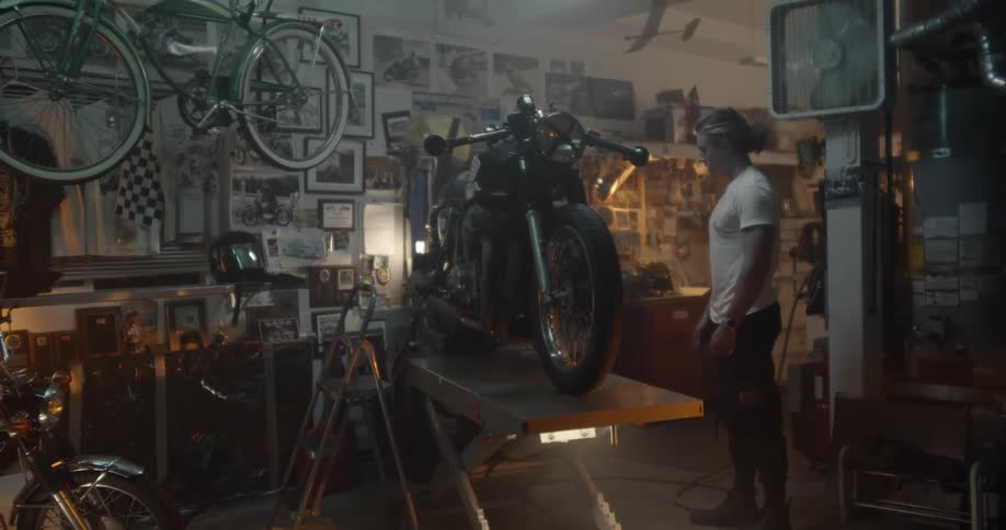 A man looks at a motorcycle in a workshop