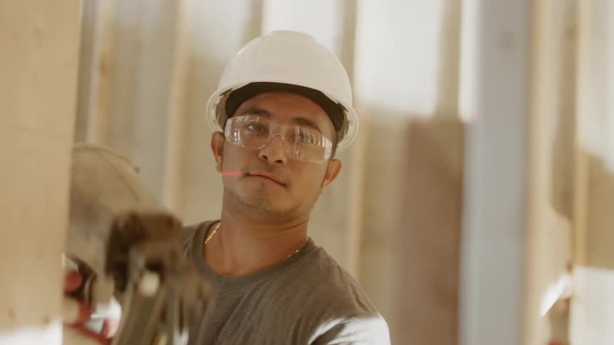 A construction worker nails wood to a frame