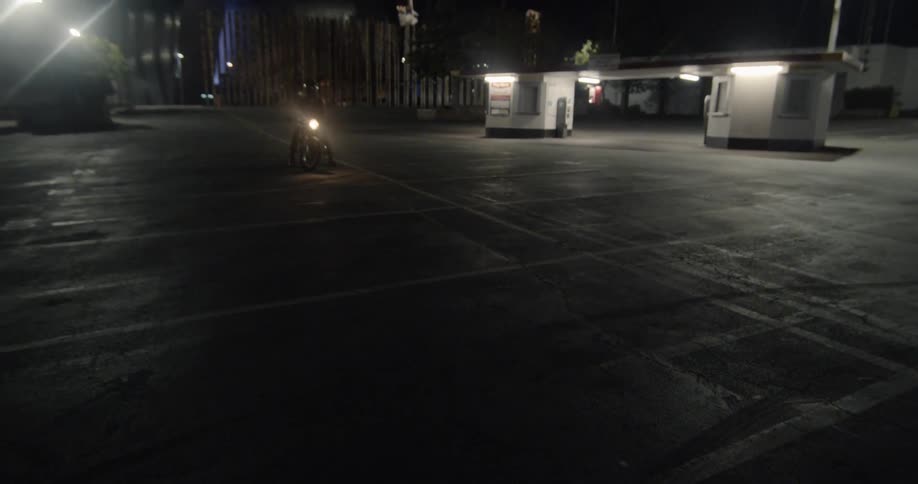The lot is dark except for a person on the motorcycle