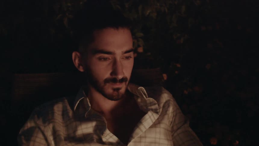 A man sits outside at night by the fire