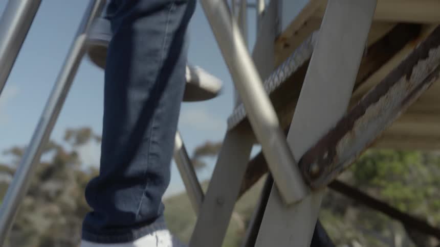 The man is climbing up the steps on the beach