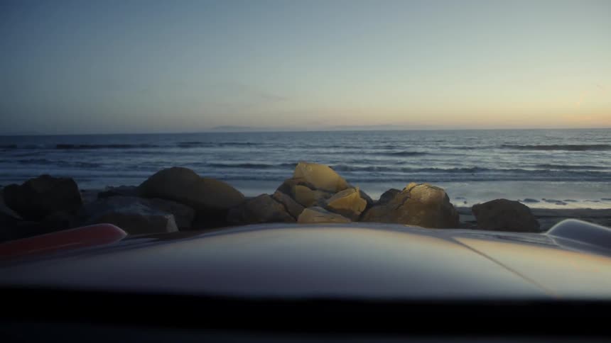 The vehicle is parked on the beach at sunset
