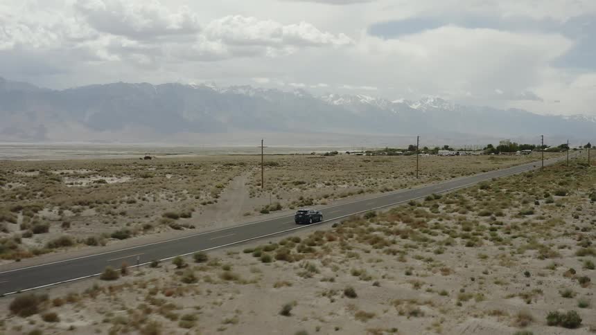 The vehicle drives down the desert road