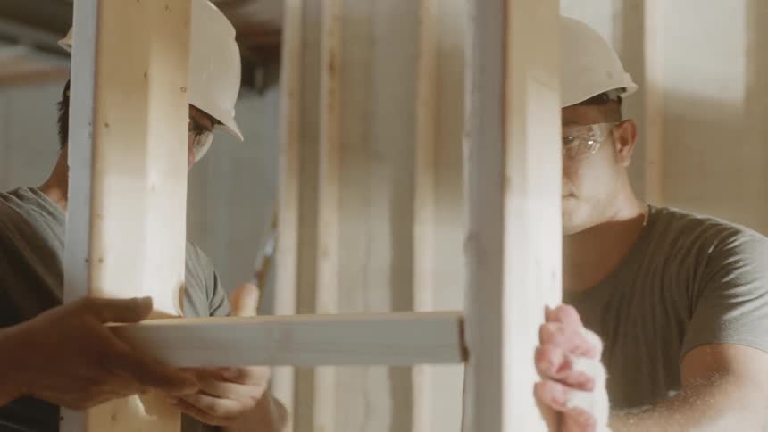 Two men work on wood framing