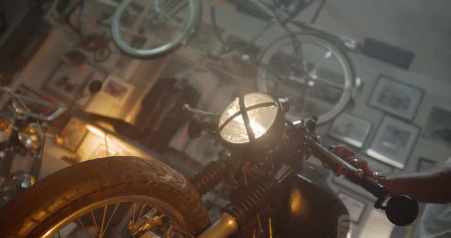 A man turns on a motorcycle headlight in a workshop