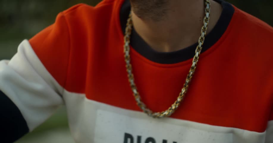 A man wears a chain necklace outside