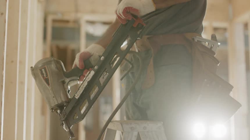 Man is putting more nails in nail gun at construction site