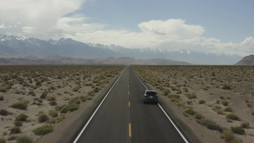 A car drives on a rural desert road