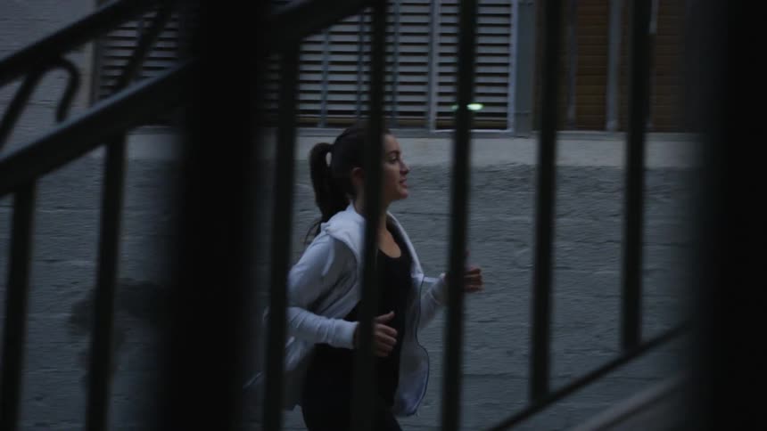 A woman is jogging past a set of stairs in a city at dusk