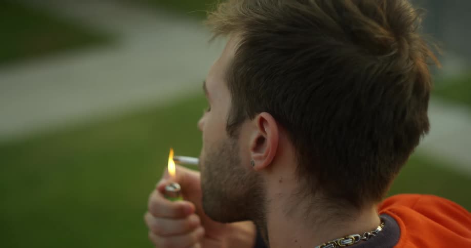 A man lights a cigarette outside