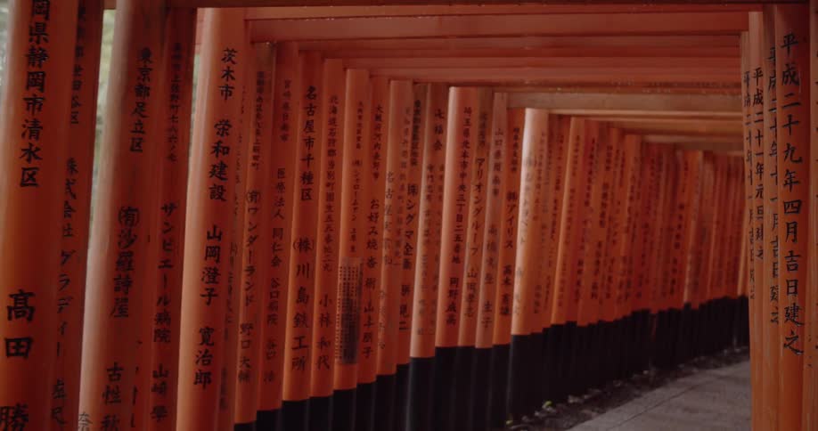 Asian characters are written on red posts on a walkway gate