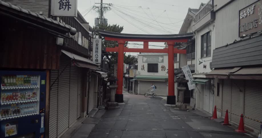 A red gate across a street with shops on both sides