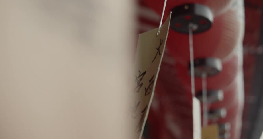 White tags hang from string in front of a red building
