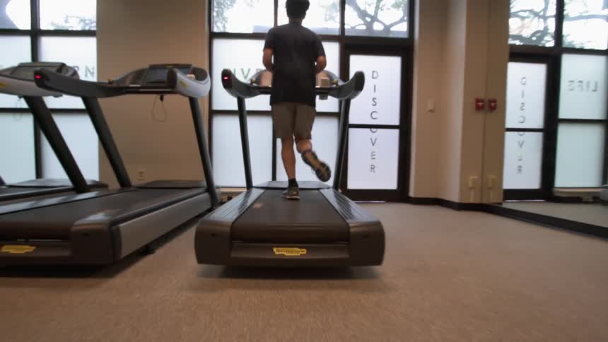 A man looks out the window while running on a treadmill