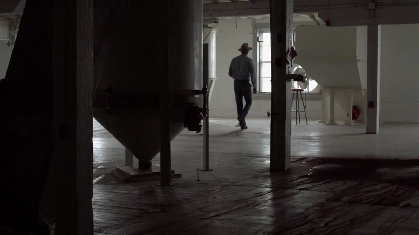 Man wearing a hat walks towards a window