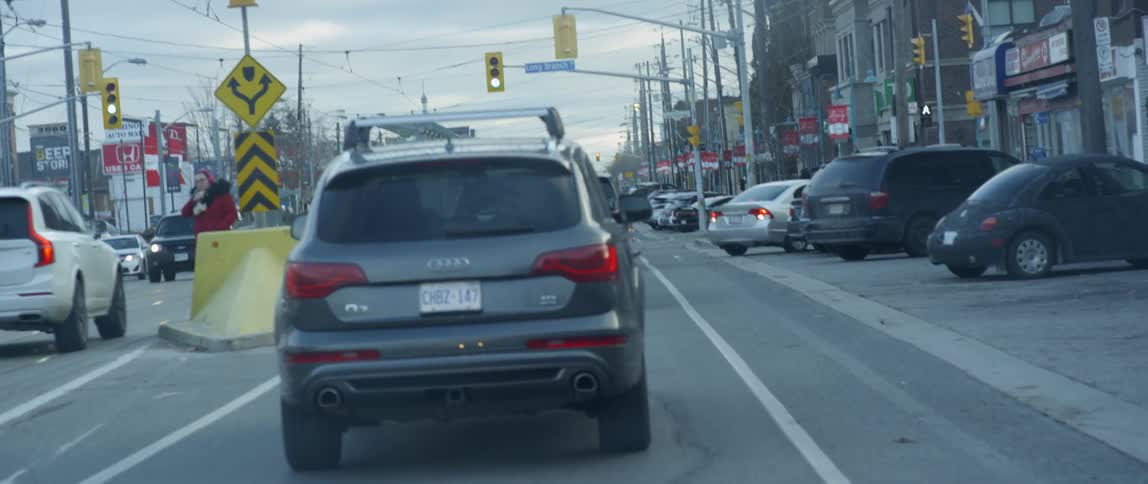 Traffic travels down the street as a car begins to back out of a parking spot