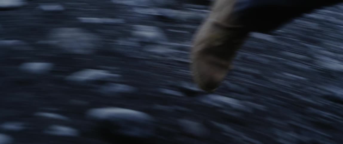 A person is walking over the rocks on the foggy field