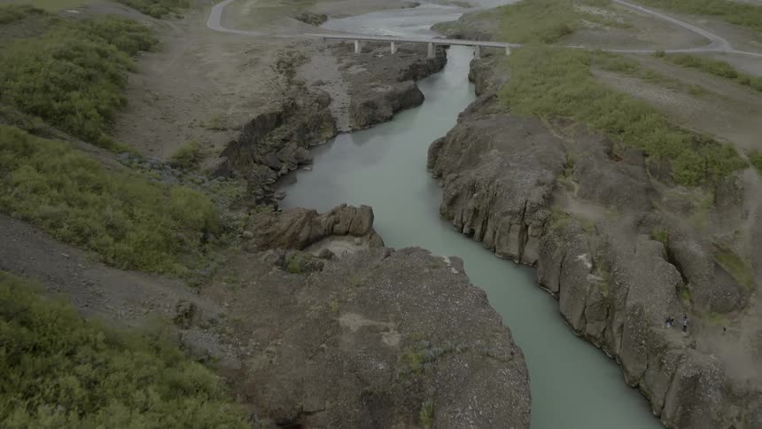 Winding canyon river flows under bridge in the country