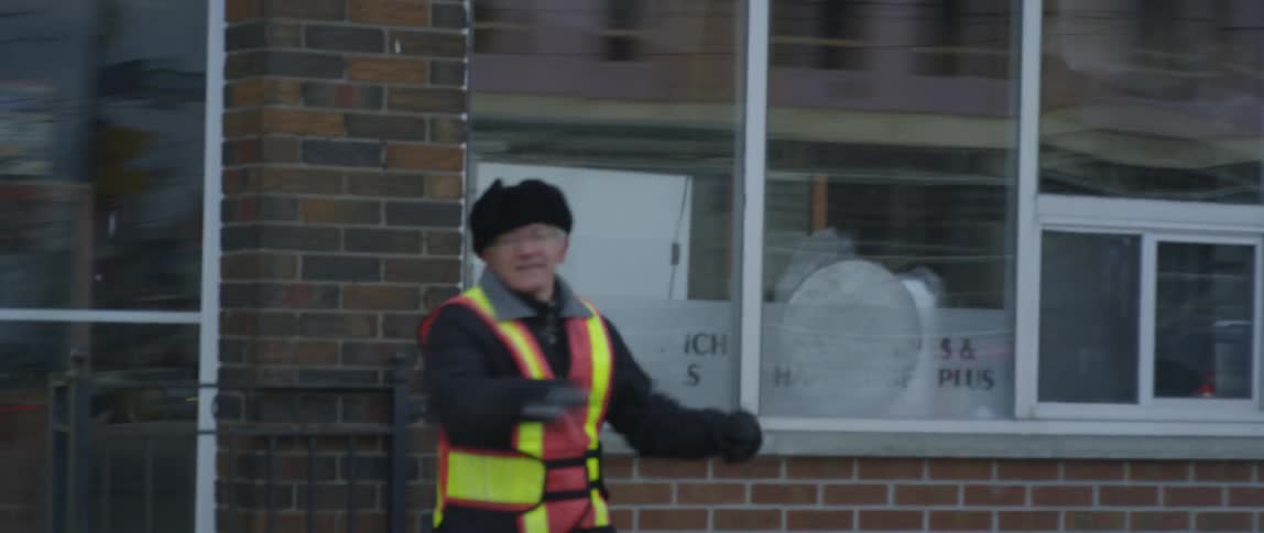 A crossing guard stretches on the street corner