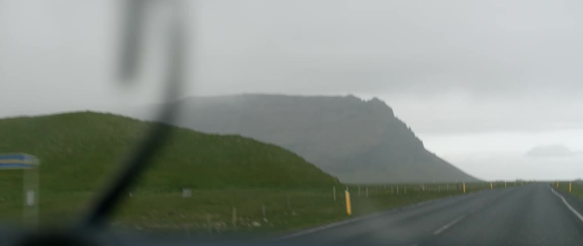 Windshield wipers going on car traveling in storm on mountain highway