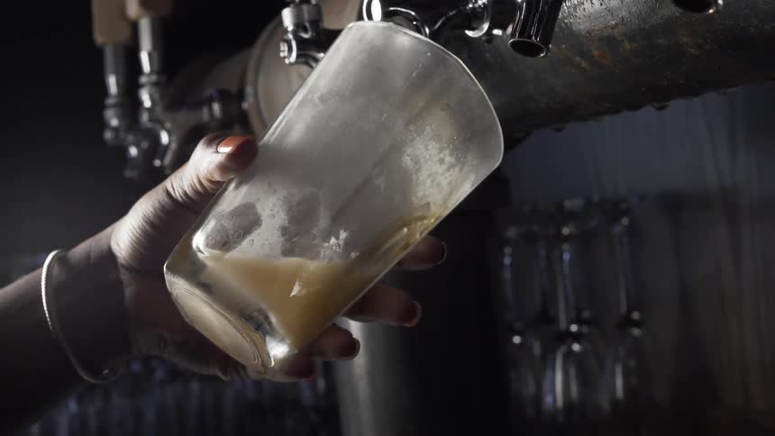 A glass of beer is poured from the tap