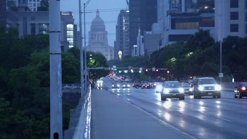 Traffic travels down the city street as darkness falls