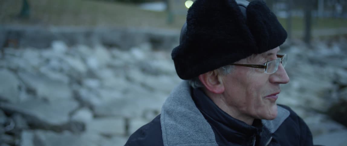 A man wearing a winter hat talks outside