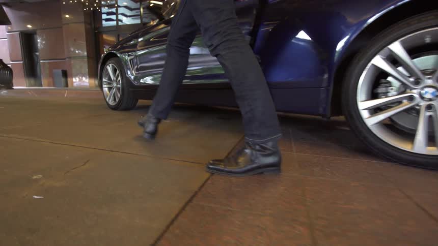 Man exits a vehicle and walks around the front of it