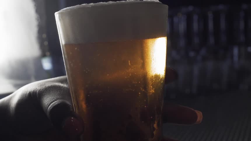 A woman holds a glass of beer