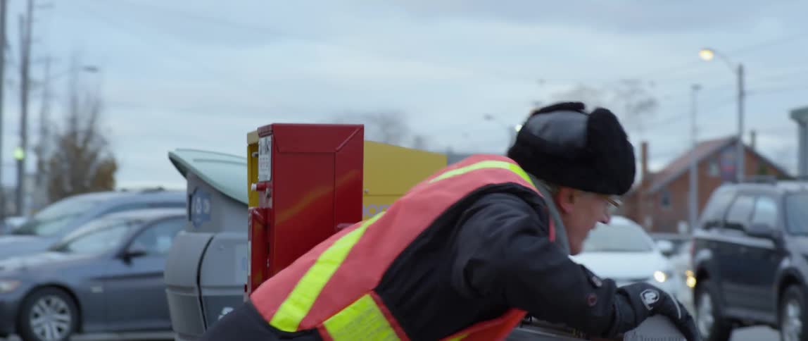 A man wearing a safety vest does push ups on the side of the road