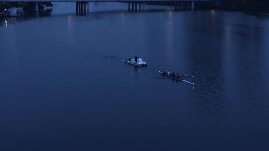 A boat trails a row boat in the water