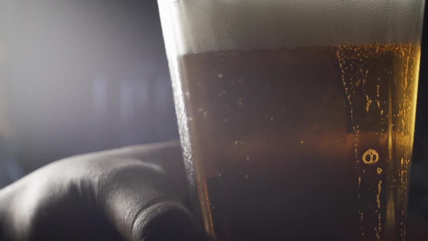 A person holds a glass filled with beer