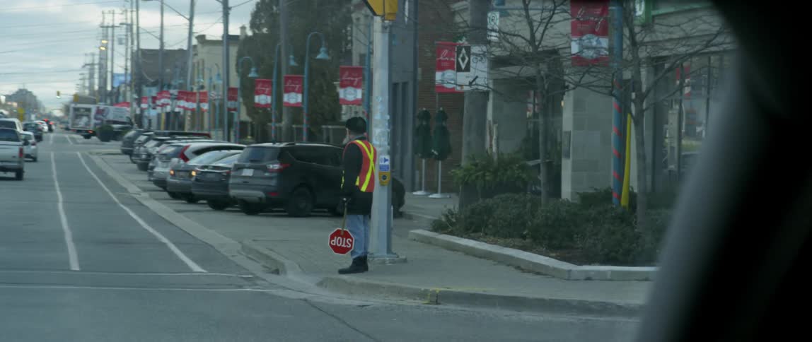 Cars pass a crossing guard on the side of the road