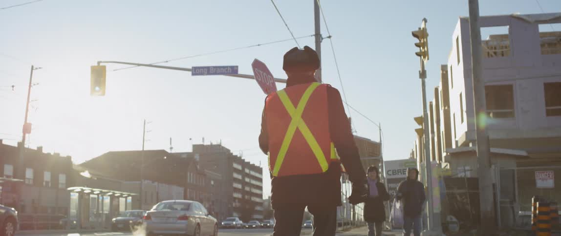 A traffic guard holds up a stop sign while pedestrians cross a street