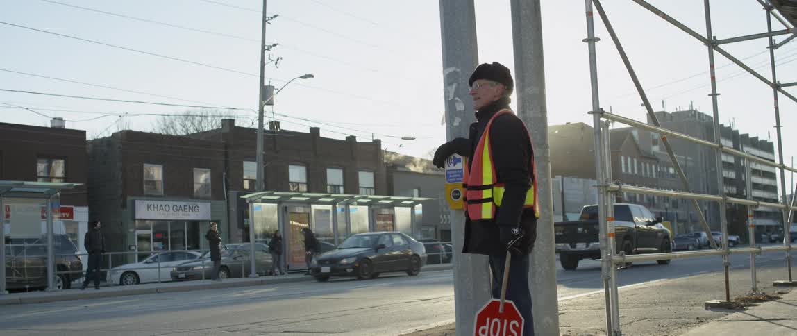 A crossing guard monitors from the street corner