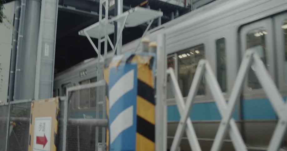 A commuter train is passing into a station in daylight