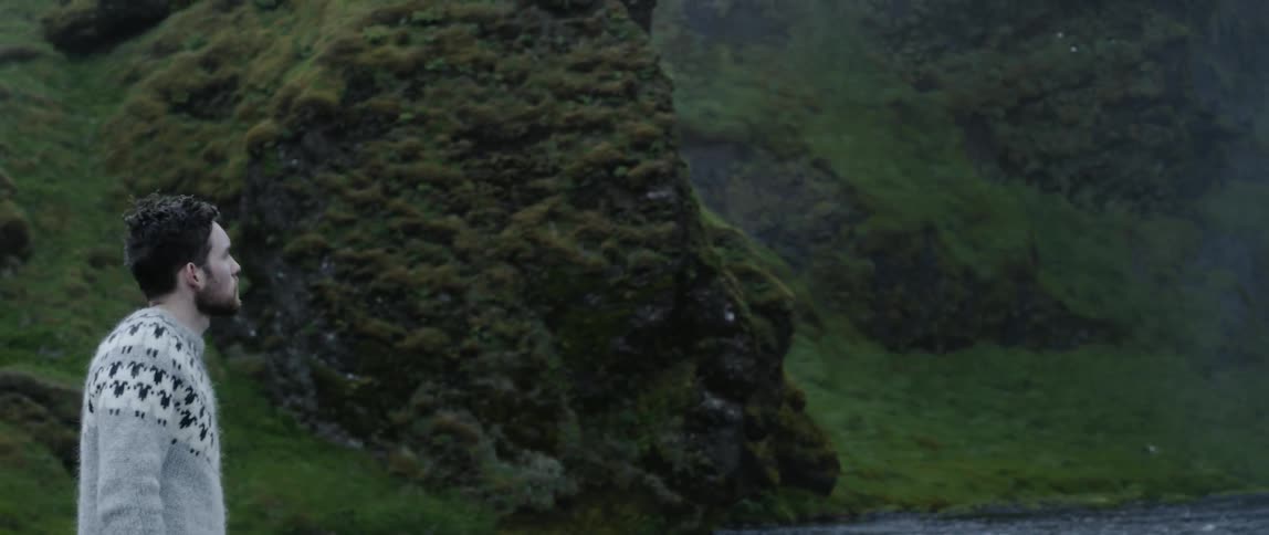 Man wearing a sweater walks next to a river