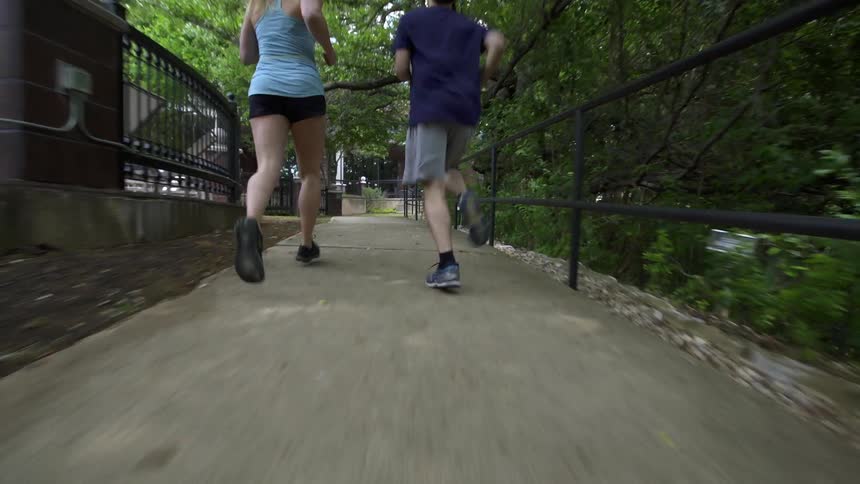 A man and woman jog on a pathway