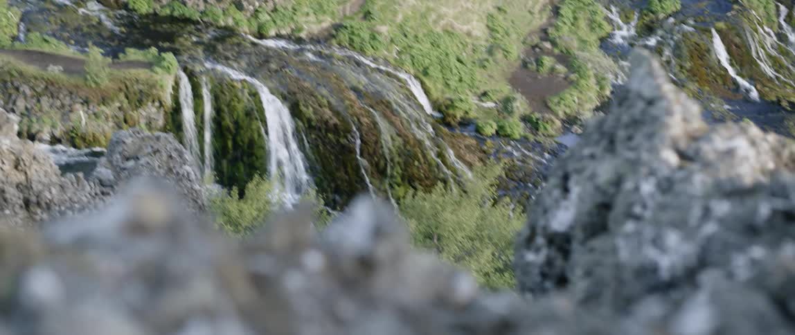 The waterfall is pouring into the stream over the rocks